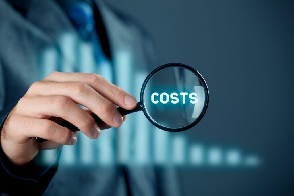 Hand mit Lupe auf dem Wort „Costs“ – Symbol für Kostenanalyse und Beitragsoptimierung bei BU-Verträgen