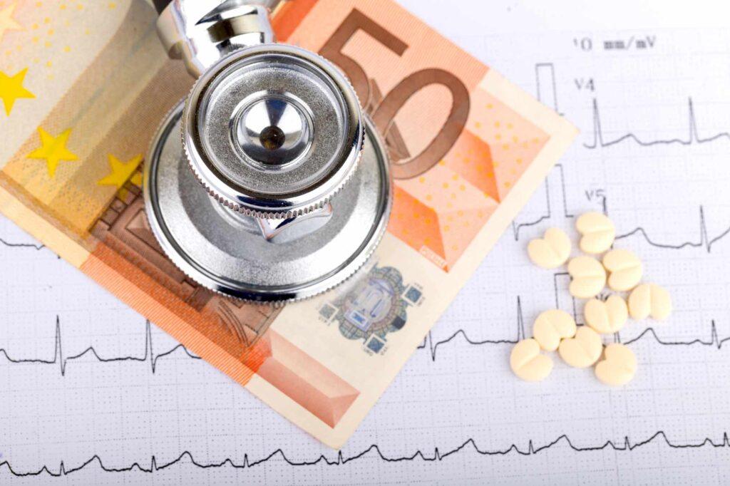 Stethoskop, Medikamente und Euro-Banknoten auf einem EKG-Ausdruck als Symbol für Kosten und Leistungen einer Krankenzusatzversicherung.