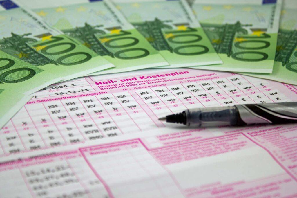 Euro-Banknoten auf einem Heil- und Kostenplan beim Zahnarzt als Symbol für Krankenzusatzversicherung und Gesundheitskosten.