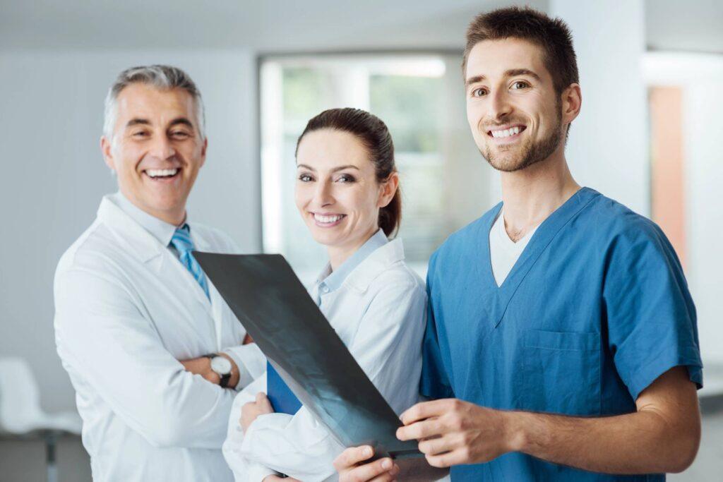 Ärzteteam in einer Klinik mit Röntgenbild als Symbol für medizinische Versorgung und private Krankenversicherung für Beamte.
