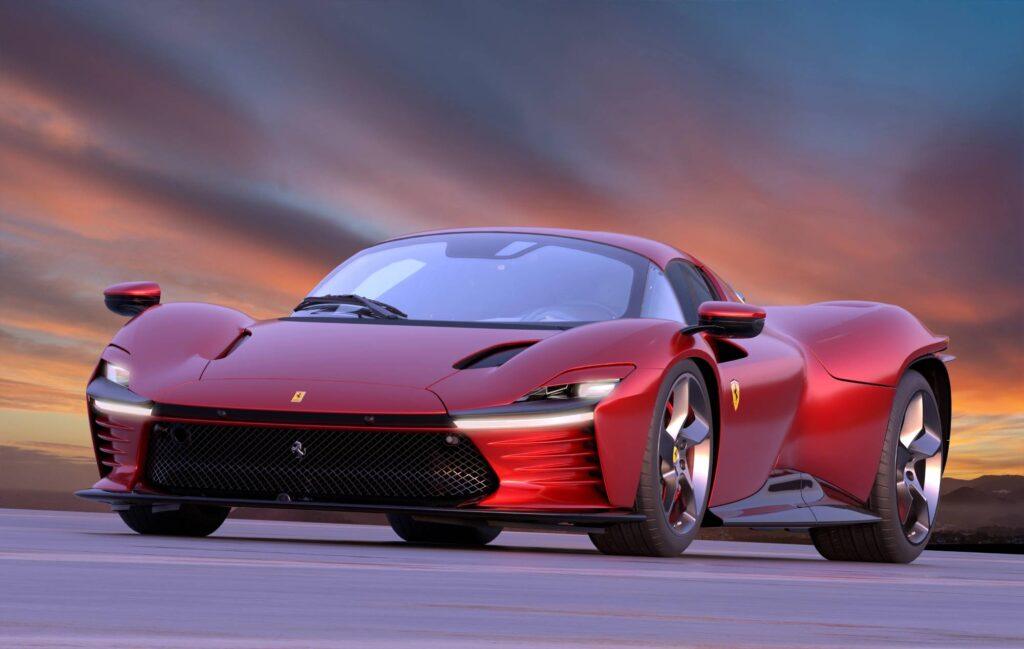 Roter Ferrari Daytona SP3 in schräger Frontansicht vor dramatischem Sonnenuntergang mit markanter Frontpartie und breiter Sportwagen-Silhouette.